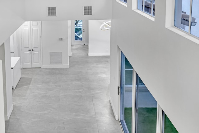 interior space with visible vents, a towering ceiling, and baseboards