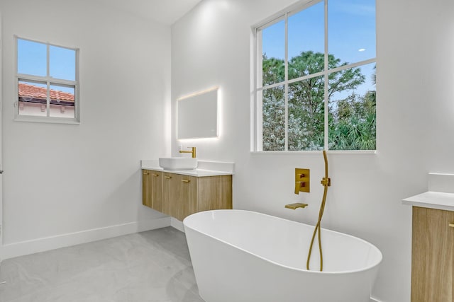 full bathroom with a freestanding tub, baseboards, and vanity