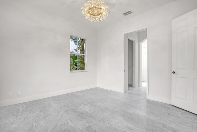 spare room featuring a chandelier, visible vents, and baseboards