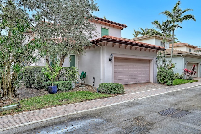 view of property exterior featuring an attached garage, a tile roof, decorative driveway, and stucco siding