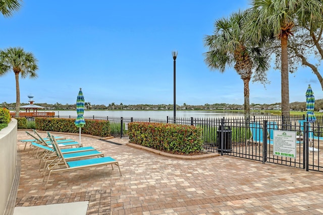 view of patio with a water view and fence