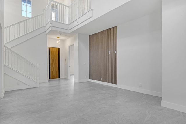 interior space with stairs, a high ceiling, finished concrete flooring, and baseboards