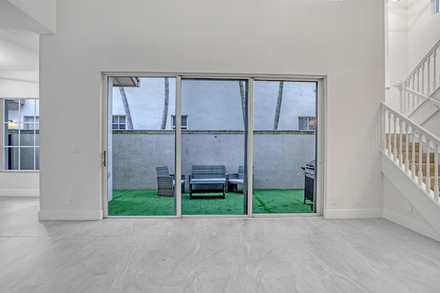 empty room featuring baseboards, stairs, and a high ceiling