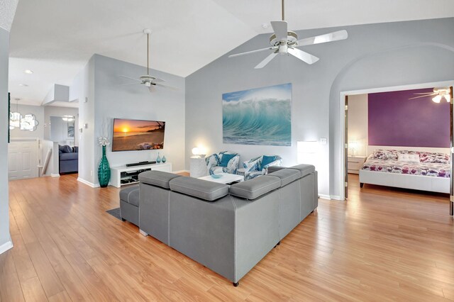 living area with vaulted ceiling, ceiling fan, light wood finished floors, and baseboards