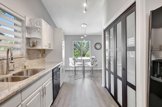 kitchen with a textured ceiling, a sink, white cabinets, black dishwasher, and tasteful backsplash