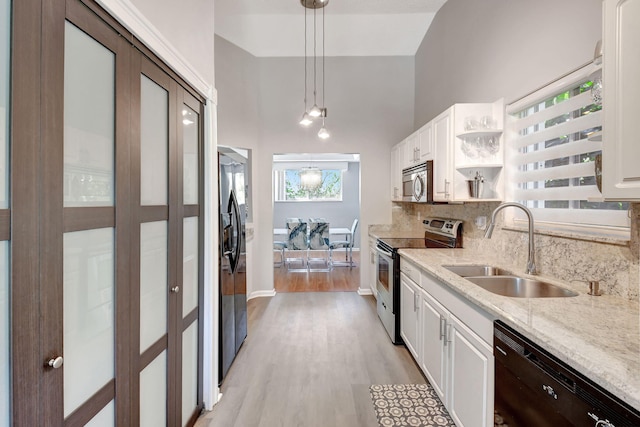 kitchen with light wood finished floors, decorative backsplash, white cabinets, a sink, and black appliances