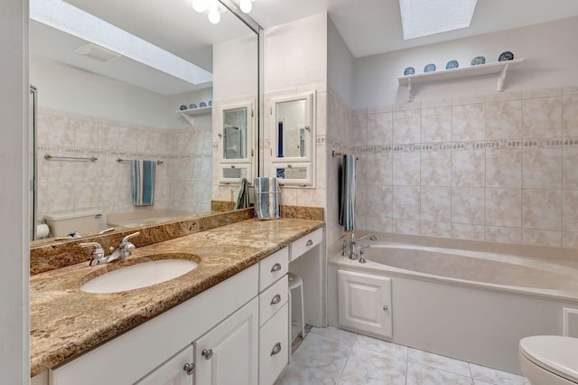 full bathroom featuring a garden tub, toilet, a skylight, vanity, and tile walls