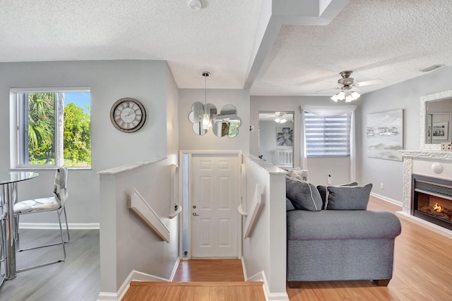 entrance foyer featuring visible vents, a glass covered fireplace, light wood-style flooring, and baseboards