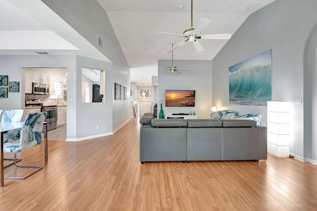 living room featuring light wood-style floors, arched walkways, and baseboards