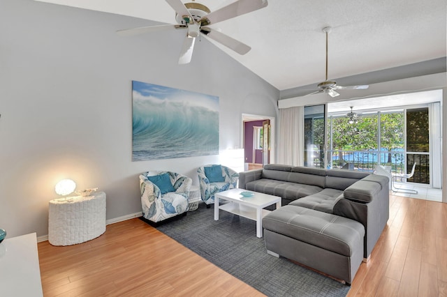 living room featuring high vaulted ceiling, baseboards, and wood finished floors