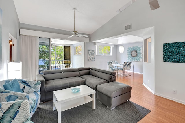 living room featuring light wood finished floors, visible vents, a ceiling fan, high vaulted ceiling, and baseboards