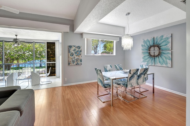 dining area with wood-type flooring, a textured ceiling, baseboards, and ceiling fan with notable chandelier