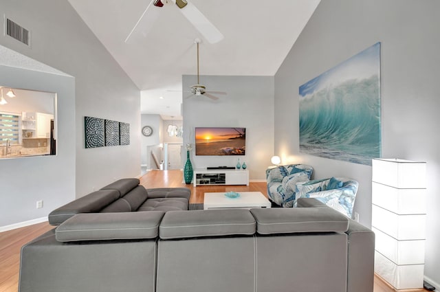 living area featuring a ceiling fan, visible vents, vaulted ceiling, and wood finished floors