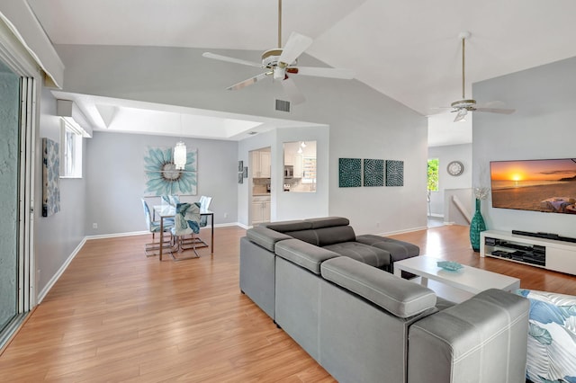 living room with visible vents, baseboards, ceiling fan, light wood-type flooring, and high vaulted ceiling