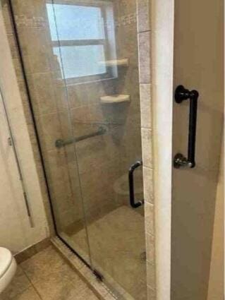 full bathroom with a stall shower, tile patterned flooring, and toilet