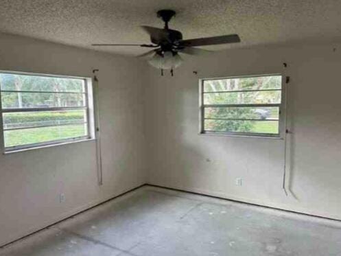 empty room with a wealth of natural light, concrete floors, and a textured ceiling