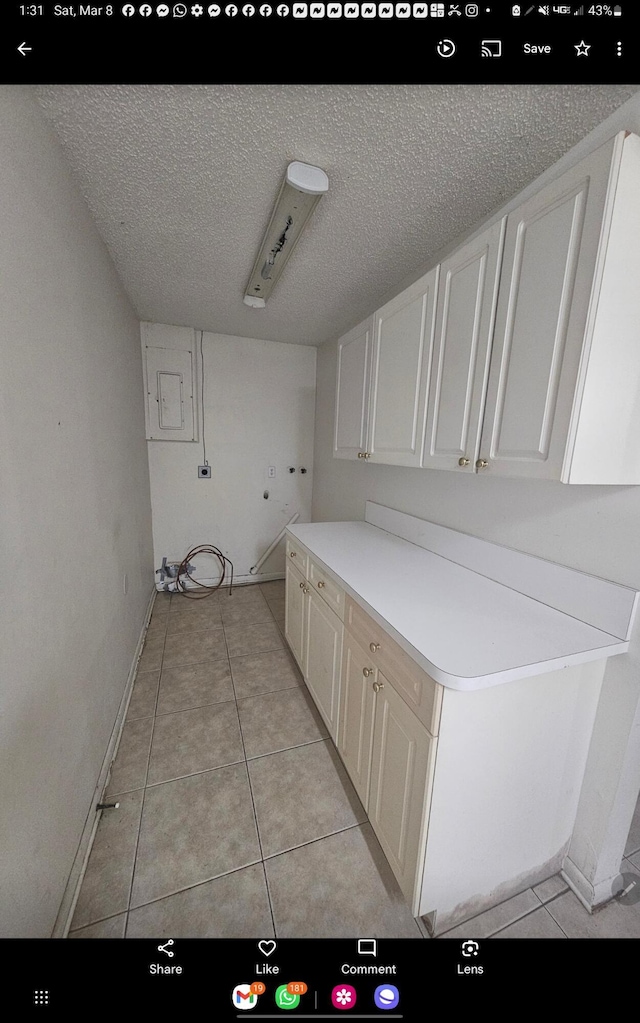 clothes washing area with washer hookup, cabinet space, a textured ceiling, and light tile patterned flooring