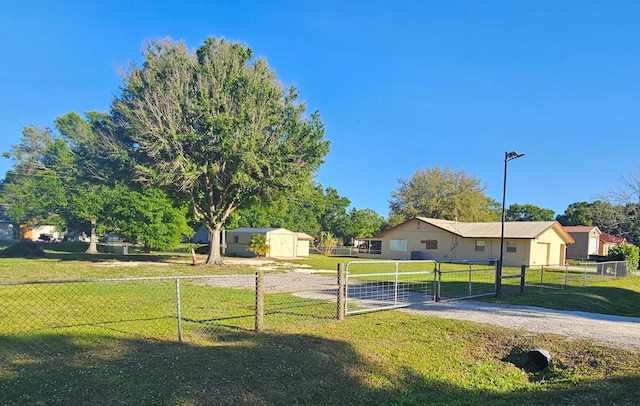 view of yard featuring a shed, an outdoor structure, fence, and a gate