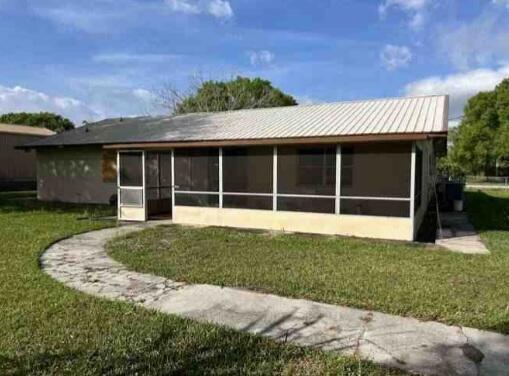 view of side of property featuring metal roof, a lawn, and stucco siding