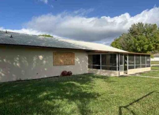 rear view of property with a lawn and a sunroom