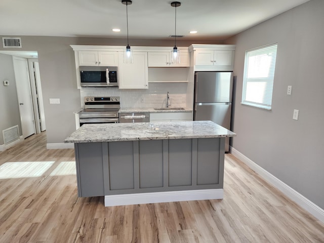 kitchen with visible vents, stainless steel appliances, a sink, and a center island