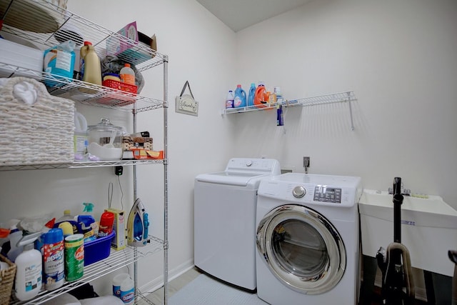 laundry room featuring a sink, laundry area, washing machine and clothes dryer, and baseboards