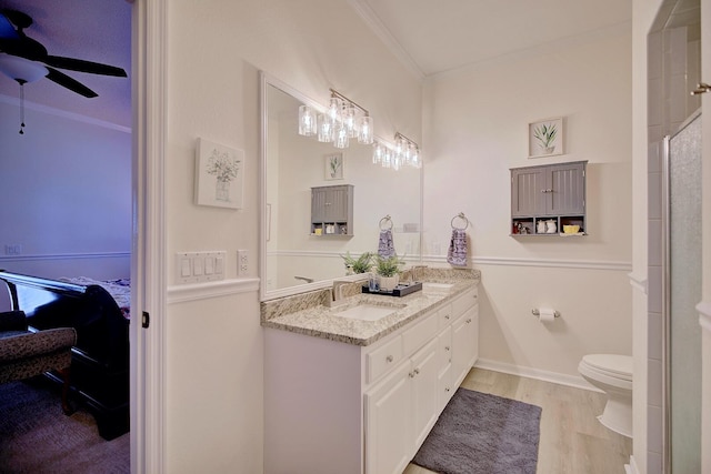 ensuite bathroom with ceiling fan, toilet, wood finished floors, ornamental molding, and ensuite bath