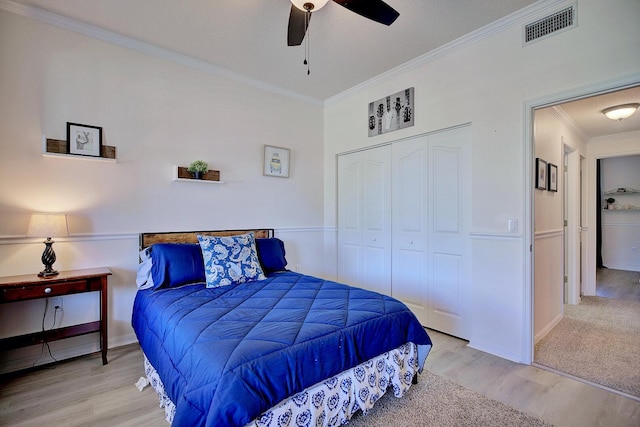 bedroom featuring a closet, visible vents, ornamental molding, ceiling fan, and wood finished floors