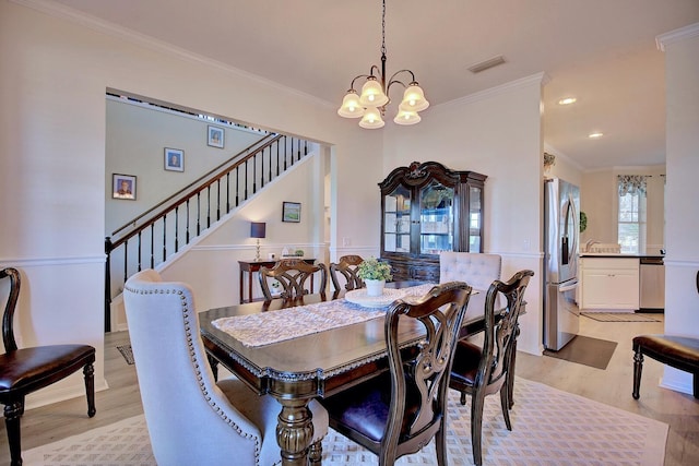 dining room with light wood finished floors, visible vents, stairs, crown molding, and a notable chandelier