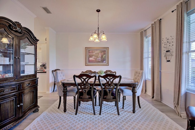 dining room with a chandelier, light wood-type flooring, visible vents, and crown molding