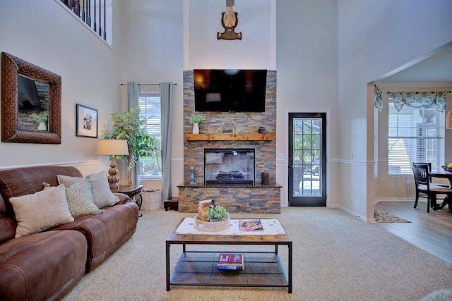 living room featuring plenty of natural light, a fireplace, and a high ceiling