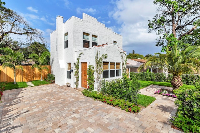 view of front facade with fence and stucco siding