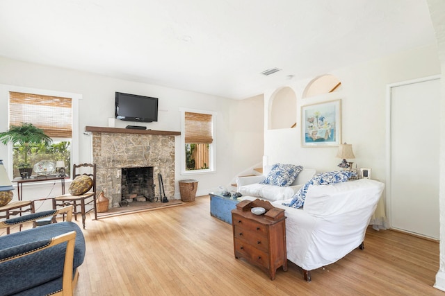 living room with stairway, visible vents, a fireplace, and light wood-style flooring