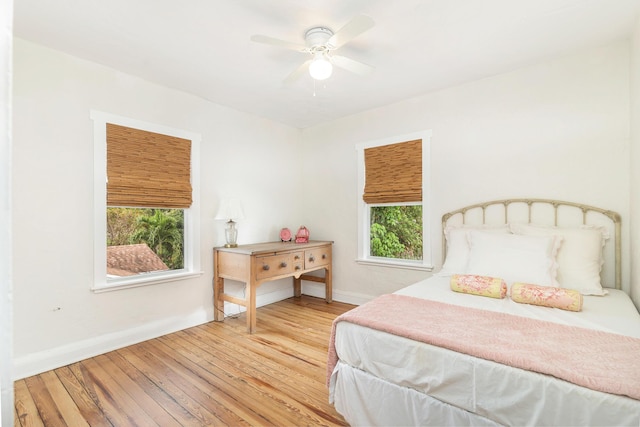 bedroom with light wood finished floors, a ceiling fan, and baseboards