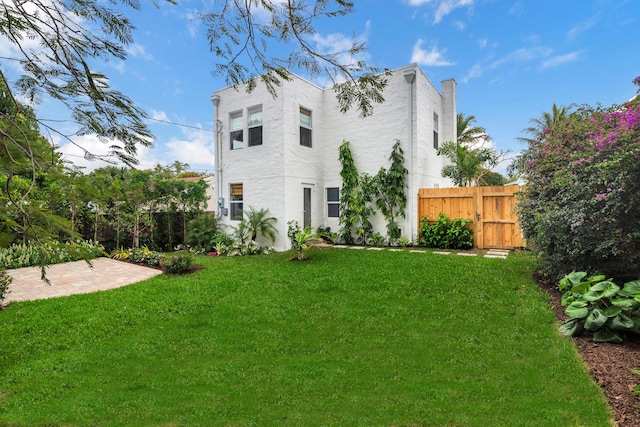 back of house featuring a yard, a patio area, fence, and stucco siding