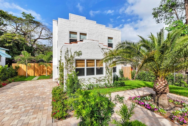 view of front facade with fence and stucco siding