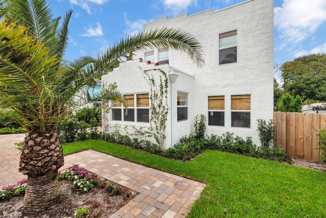 view of front of house with fence, a front lawn, and stucco siding