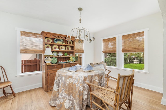 dining space with light wood-style floors, baseboards, and an inviting chandelier