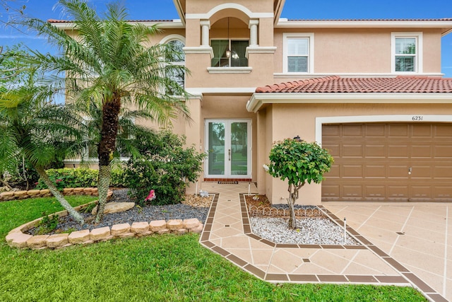 view of front of property with an attached garage, stucco siding, concrete driveway, french doors, and a tile roof