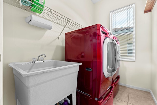 laundry area featuring light tile patterned floors, baseboards, laundry area, a sink, and independent washer and dryer