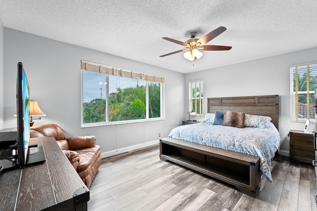 bedroom with ceiling fan, a textured ceiling, and wood finished floors