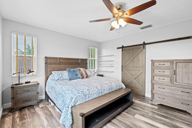 bedroom with baseboards, a barn door, and wood finished floors