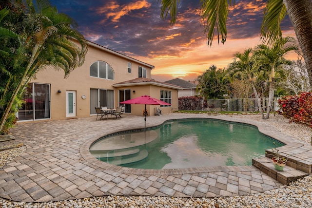 pool at dusk with a patio area, a fenced in pool, and a fenced backyard