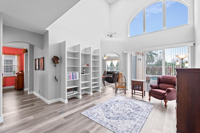 living area with a ceiling fan, wood finished floors, arched walkways, and baseboards