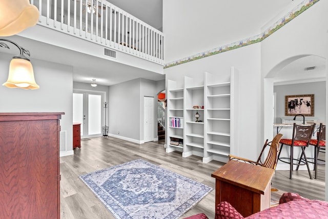 living room featuring visible vents, a high ceiling, baseboards, and wood finished floors