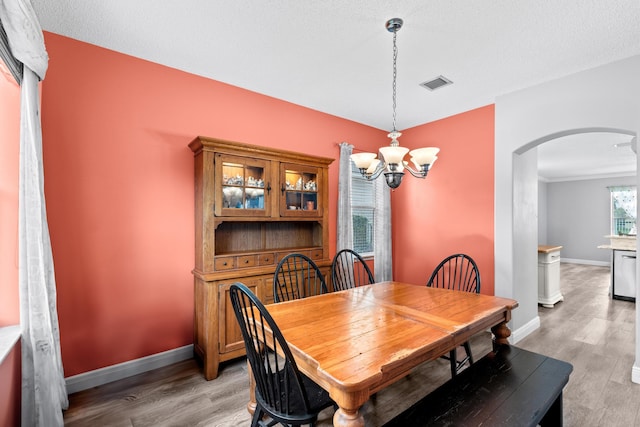 dining room with light wood-type flooring, visible vents, arched walkways, and baseboards