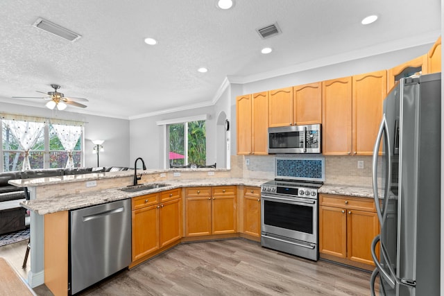 kitchen with visible vents, light wood-type flooring, appliances with stainless steel finishes, a peninsula, and a sink