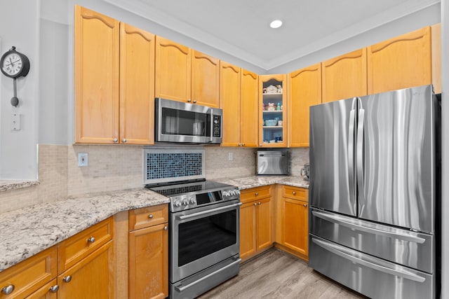 kitchen with decorative backsplash, light wood-style floors, appliances with stainless steel finishes, glass insert cabinets, and light stone countertops