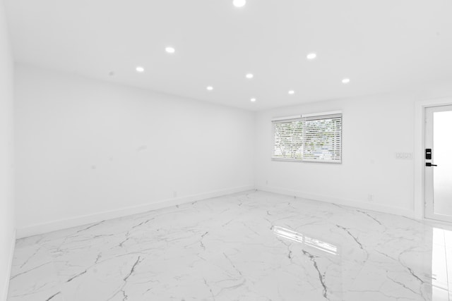 spare room with recessed lighting and baseboards