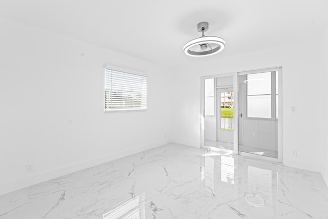 unfurnished room featuring marble finish floor, a ceiling fan, and baseboards